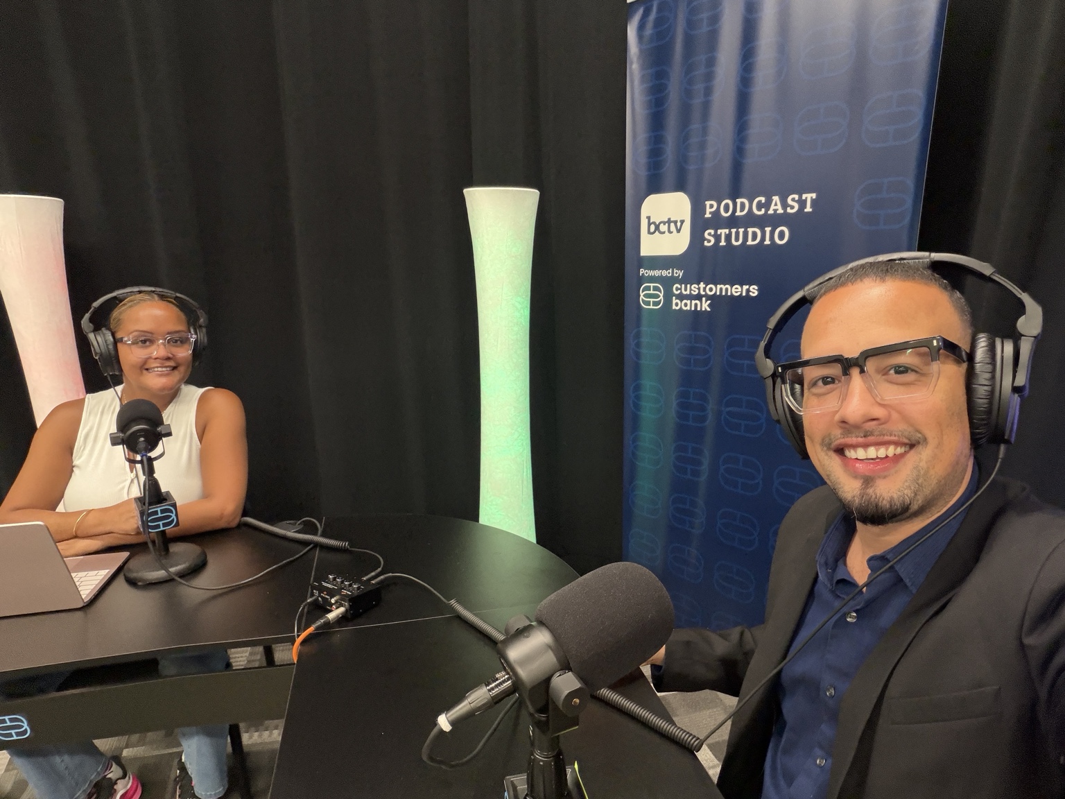 Jaime and a fellow guest wearing headphones at microphones in the BCTV podcast studio